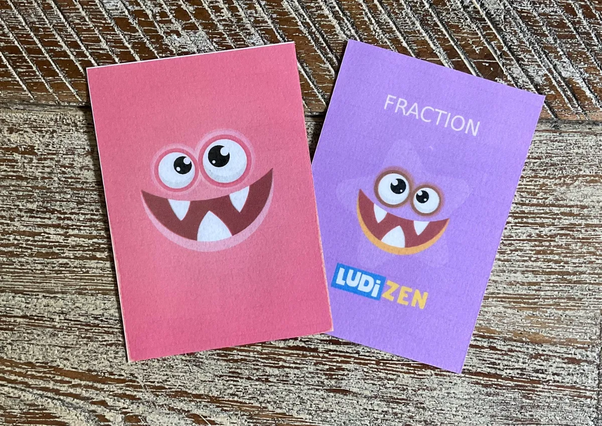 Deux cartes du Mistigri des fractions : le dos avec un monstre rigolo et la carte Fraction Ludizen.